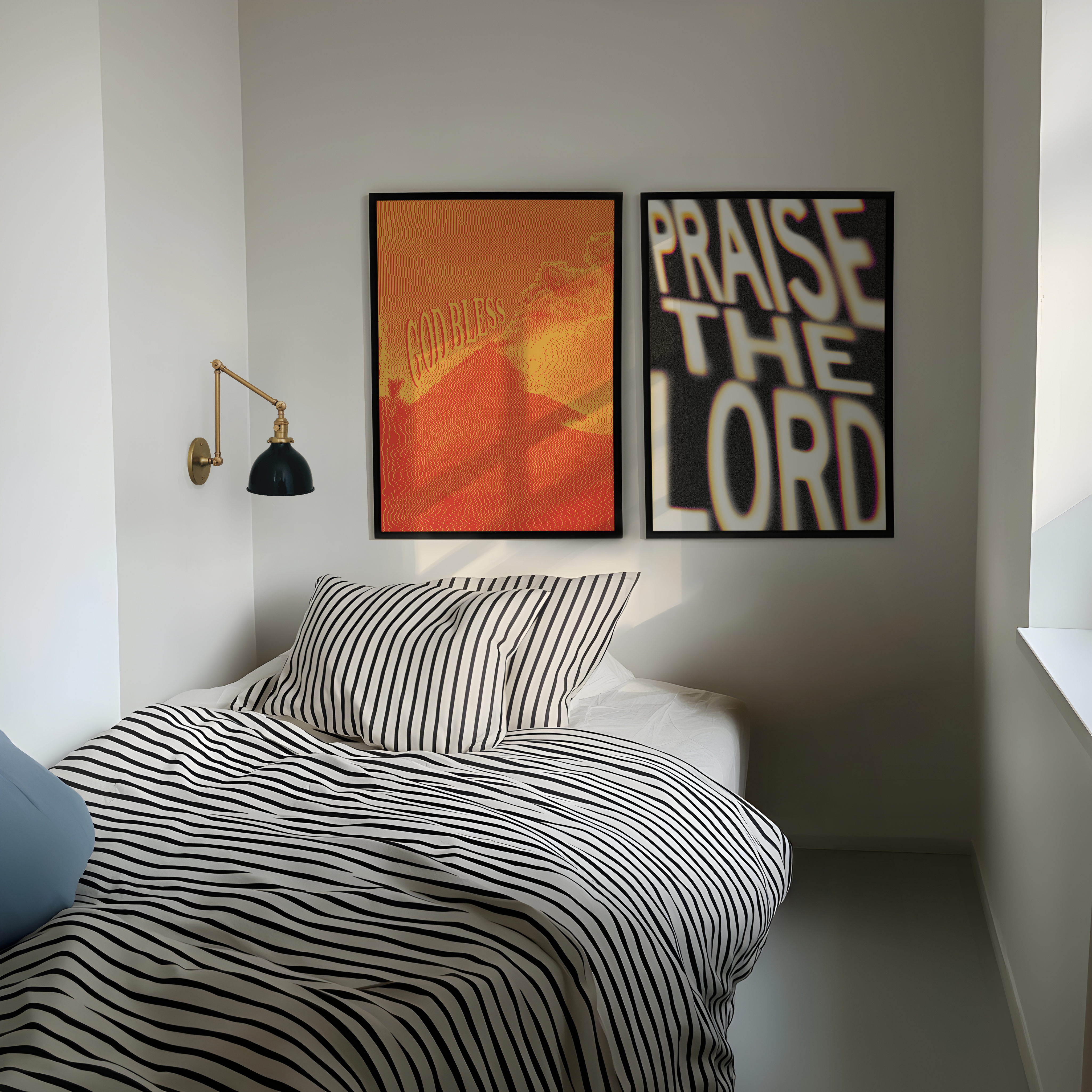 A styled bedroom corner with a bed covered in black-and-white striped bedding, a black wall lamp, and two framed wall art prints above the headboard. One print shows an orange and yellow abstract design with the word 'Godless,' and the other has large white text reading 'PRAISE THE LORD' on a black background.